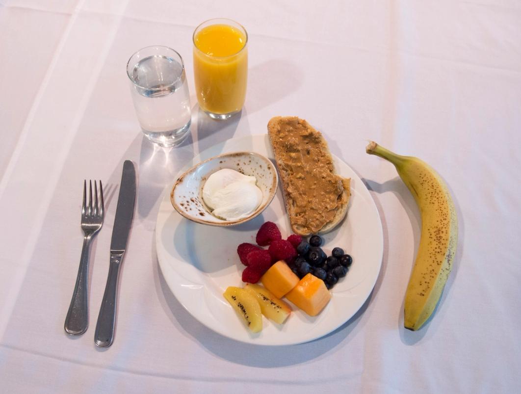 Example of the ideal gameday breakfast: Poached eggs, bread with peanut butter (protein), variety of fruit (Kiwi – Vitamin C), glass of orange juice, water & smoothie with Spinach (Iron) and Kale (not pictured).